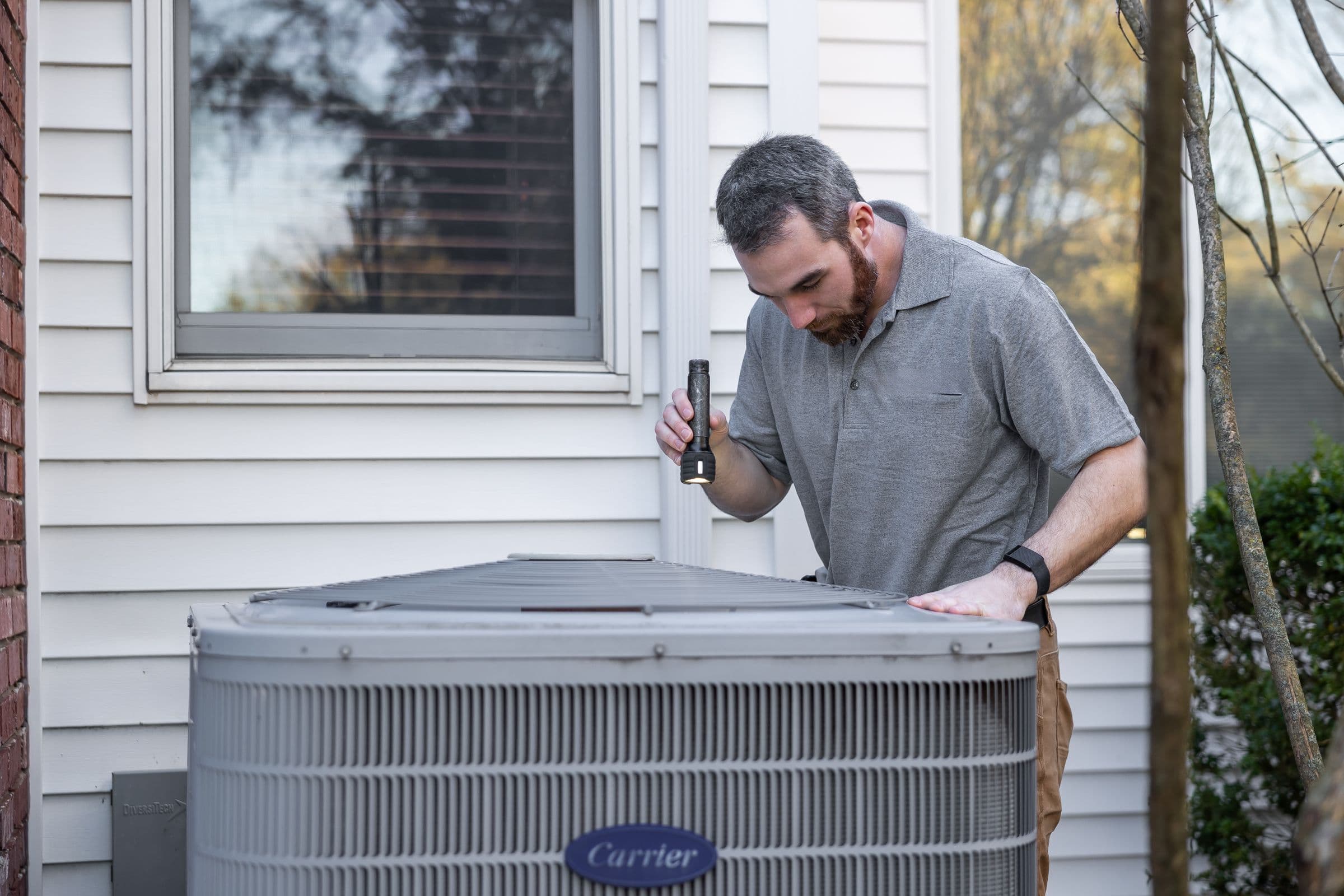 A technician inspecting an HVAC unit at a customer's home